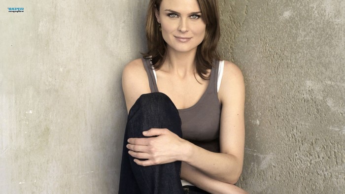 Emily Deschanel sitting against a wall