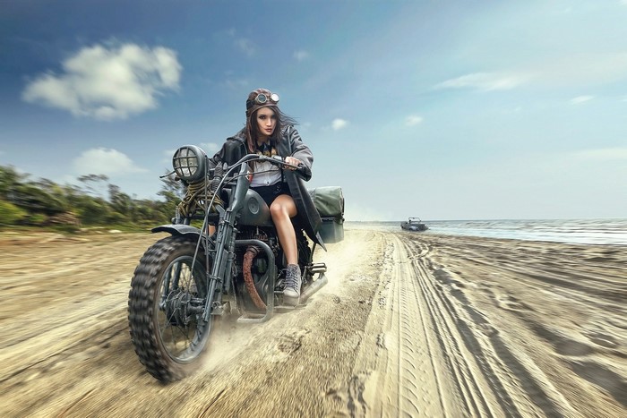 Woman riding a vintage motorcycle on a sandy beach