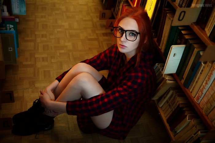 Redhead woman with glasses in a library