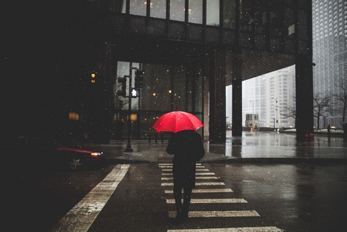 Person with red umbrella in the rain on a city street