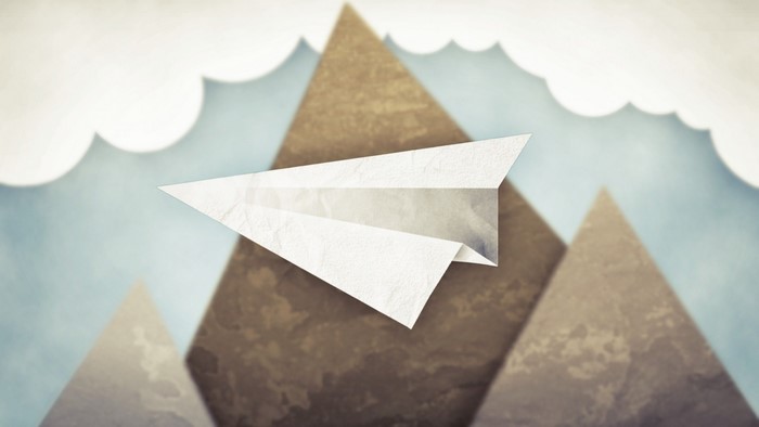 Paper airplane flying over mountains and clouds