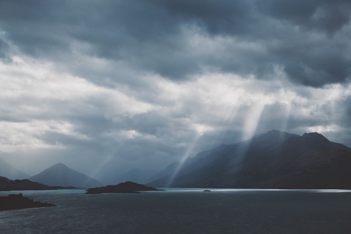 Sunbeams through clouds over mountains and a lake