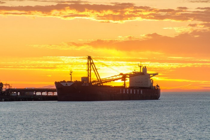 Cargo ship with cranes at sunset