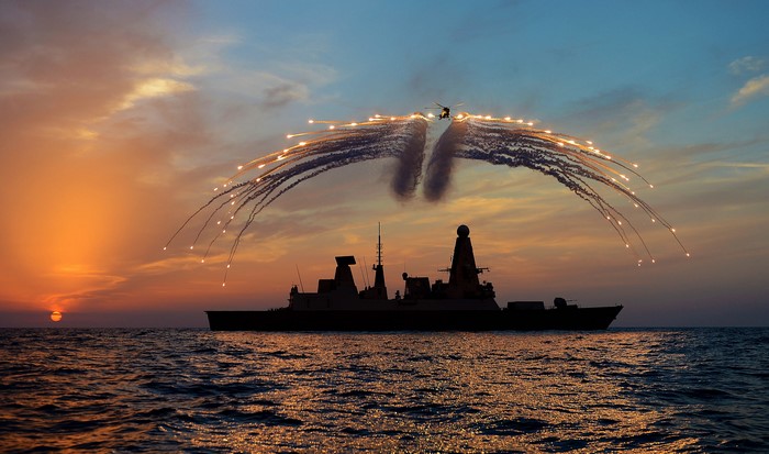 Royal Navy Type 45 destroyer firing flares at sunset