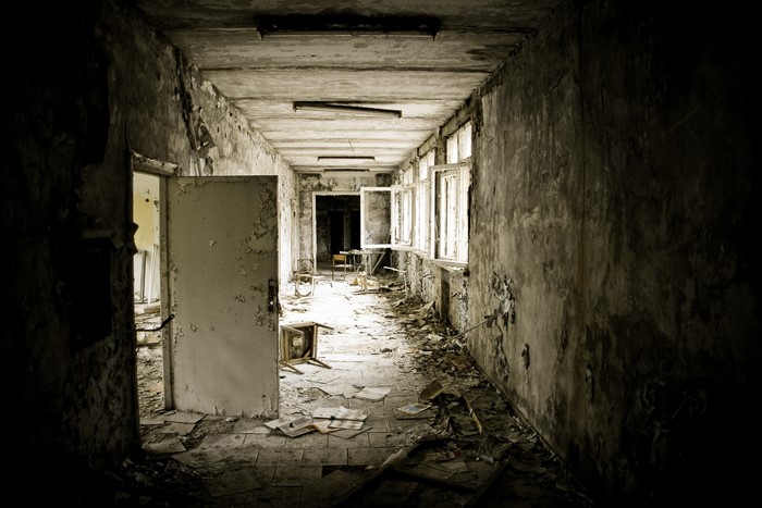 Abandoned hallway with peeling paint and debris