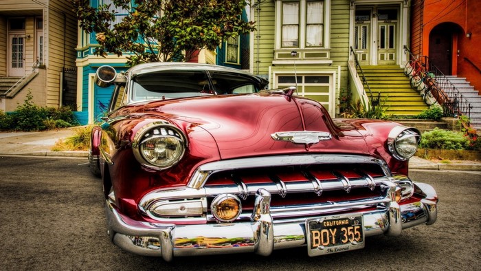 Red Chevrolet vintage car parked in front of colorful houses