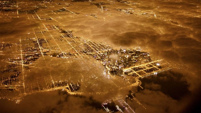 Aerial view of Chicago cityscape at night through clouds