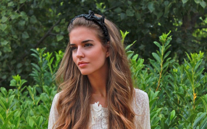 Woman with auburn hair wearing a white top and black headband