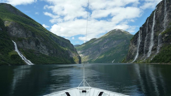 Boat sailing through Geirangerfjord with waterfalls in Norway