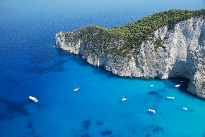 Boats in a tropical bay with cliffs and forest
