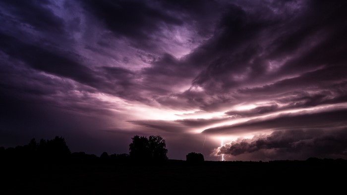 Dark clouds and lightning over silhouetted trees