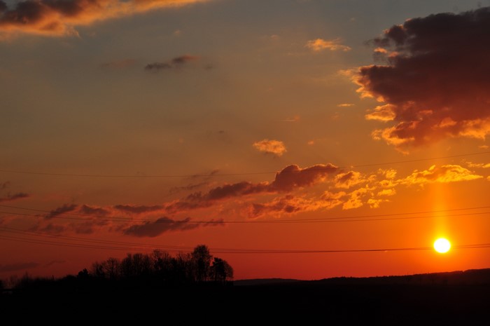 Sunset over a silhouetted landscape with power lines