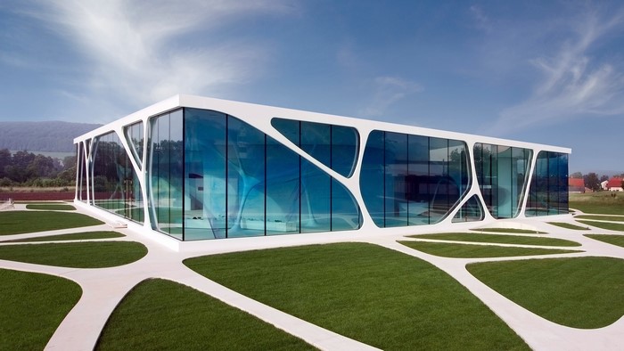 Modern glass building with white organic facade and green lawn