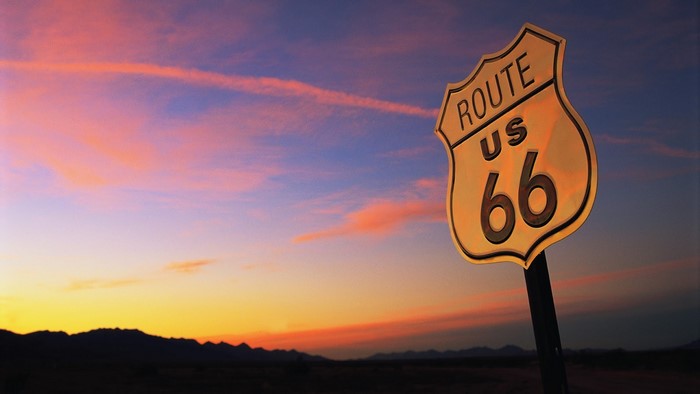Route 66 sign at sunset with mountains