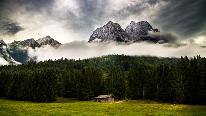 Landscape with mountains, forest, and cabin