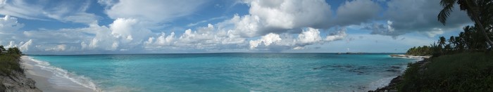 Panoramic view of a tropical beach with turquoise water and clouds