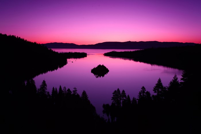 Purple sunset over a lake with an island and forest