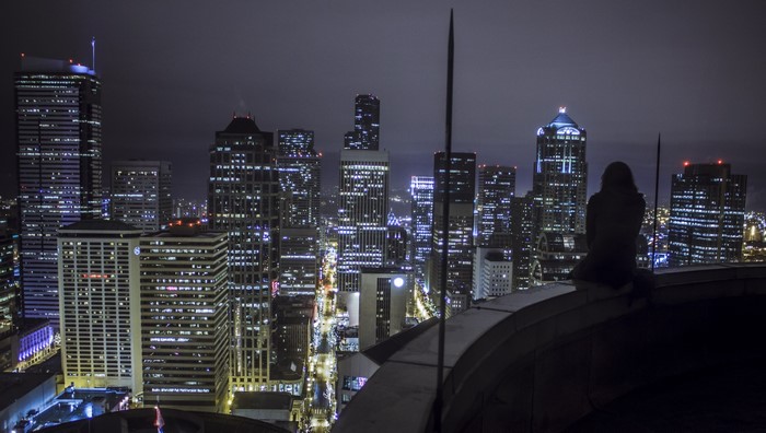 Woman on rooftop overlooking city at night