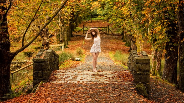 Woman in white dress on autumn bridge