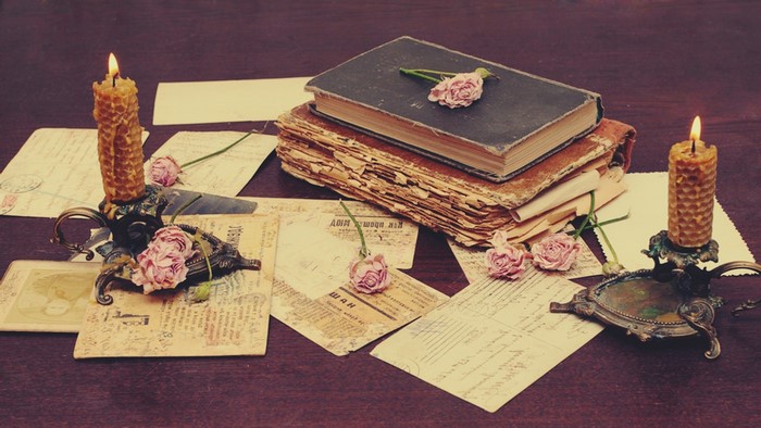 Vintage books, candles, and roses on a table