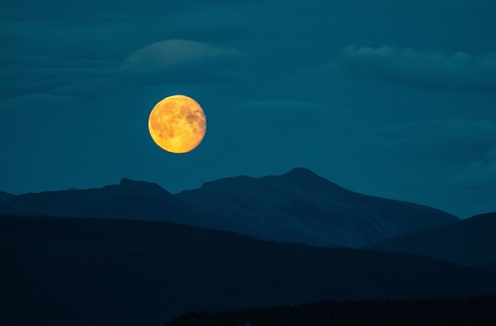 Full moon over dark mountains at night
