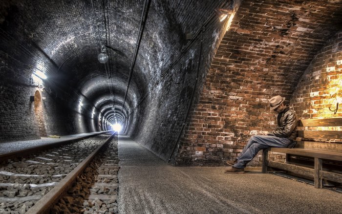 Man sitting in a brick railway tunnel