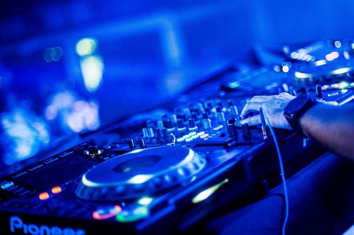 DJ hand on Pioneer mixing console with blue lights