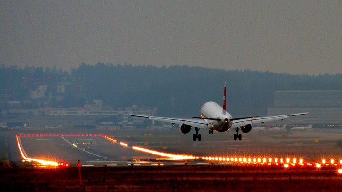 Airplane landing on runway at dusk