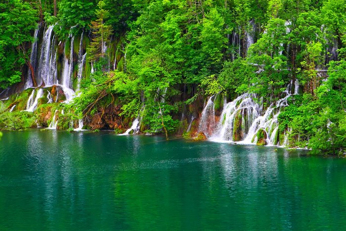 Waterfalls cascading into a turquoise lake in a lush forest