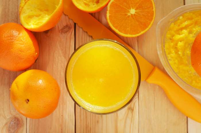 Fresh oranges and orange juice on a wooden table