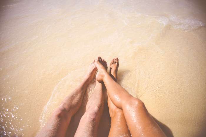 Couple's legs in the sea at the beach