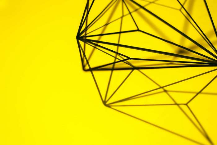 Geometric wireframe sculpture on yellow background 4K