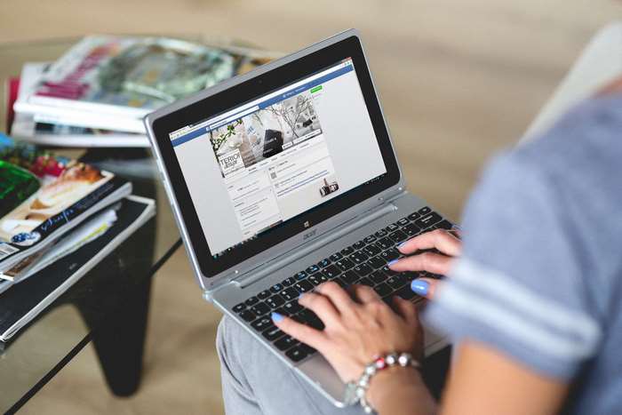 Woman typing on Acer laptop with Facebook open