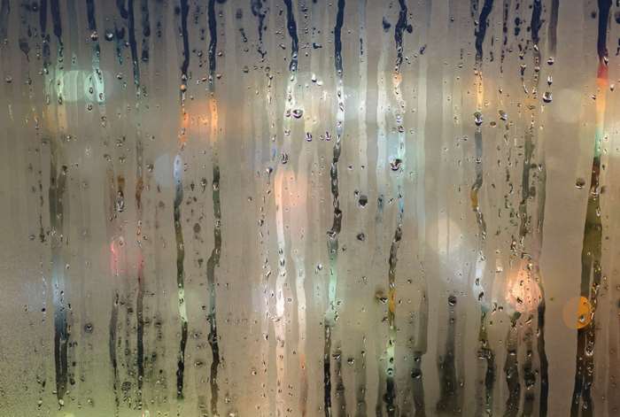 Raindrops on a foggy window with city lights