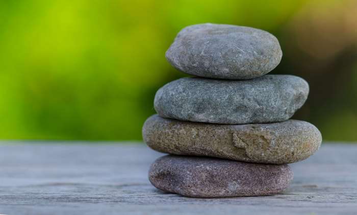 Stack of balanced stones on a wooden surface with green background