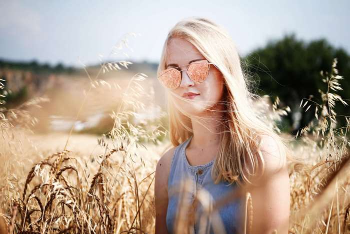 Girl with blonde hair and sunglasses in a hayfield