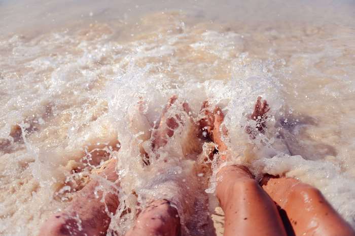 Couple's feet in ocean waves at the beach