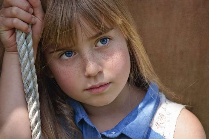 Girl with blue eyes and freckles holding a rope