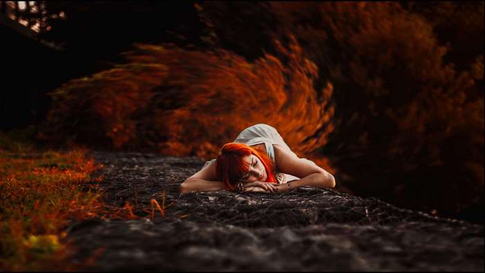 Woman with red hair lying down in nature