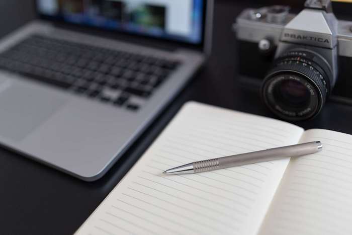 Laptop, Camera, Notebook, and Pen on Desk