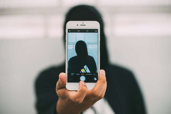 Person in a hoody taking a selfie with an iPhone
