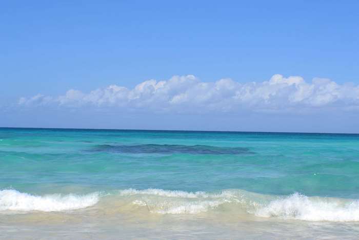 Turquoise ocean waves under a blue sky with clouds in Cuba 4K
