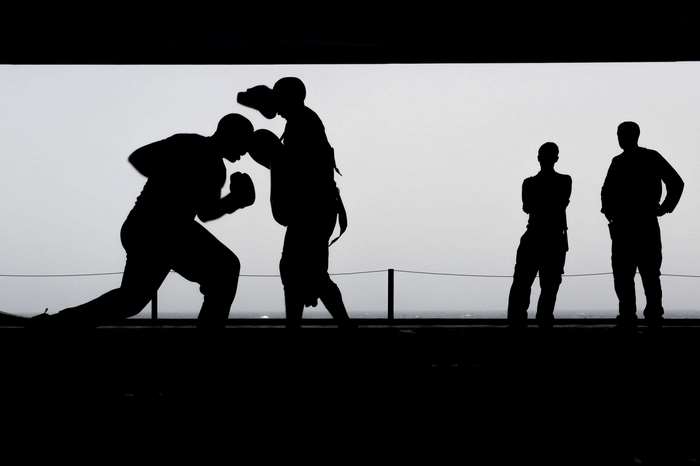 Silhouettes of boxers training with trainers watching