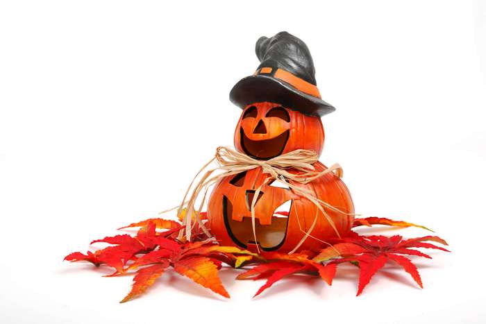 Stack of Halloween pumpkins with witch hat and autumn leaves