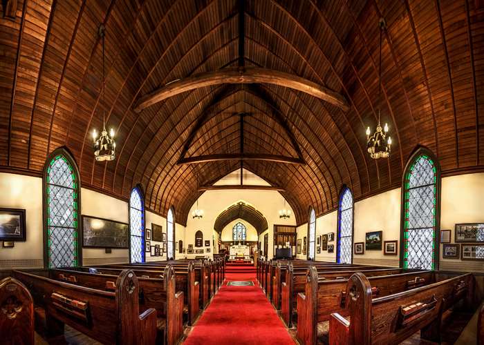 Interior of a wooden church with pews and stained glass windows