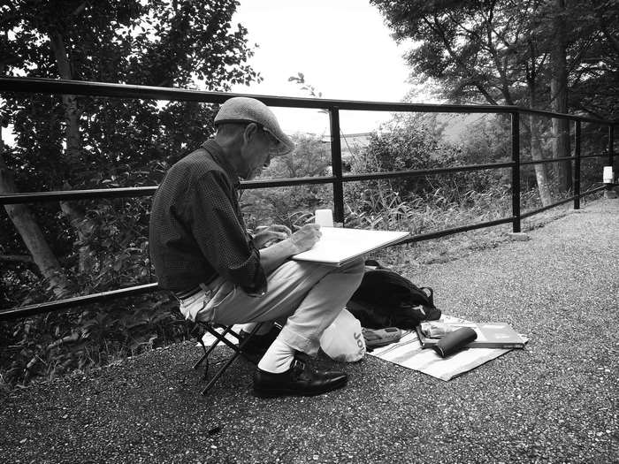 Man sketching outdoors by a fence