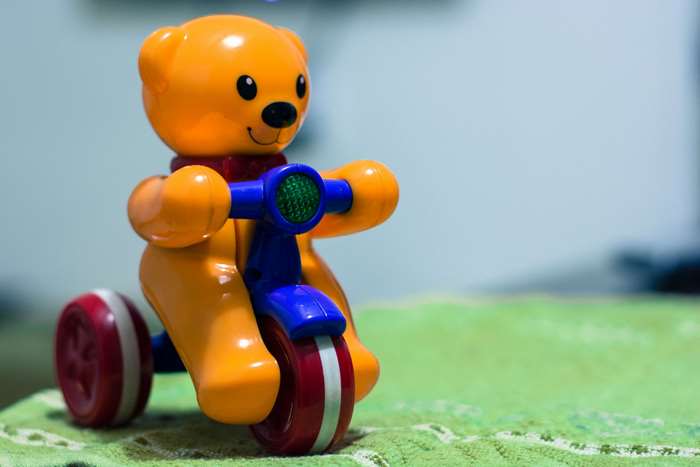 Orange teddy bear toy on a tricycle