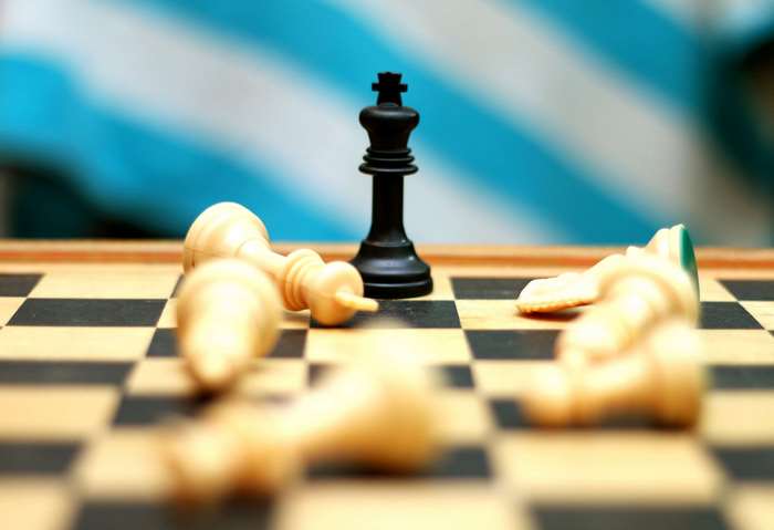 Black King stands victorious over fallen white chess pieces 4K