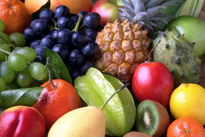 Assortment of fresh exotic fruits including pineapple, grapes, and starfruit