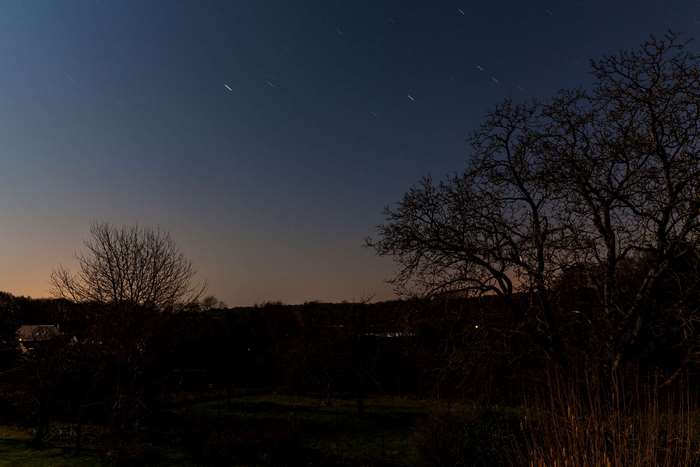 Night sky with star trails over countryside landscape
